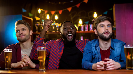 Afro-american male celebrating favorite team victory, caucasian friends upset