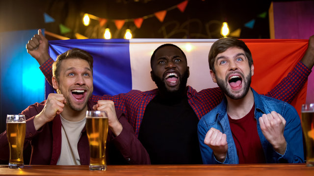 French multiracial men celebrating national team victory holding flag tournament