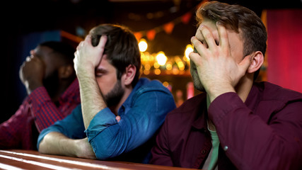 Multiethnic football fans making facepalm, disappointed with game loss, bar