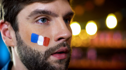 French man with painted flag on cheek supporting national during hard times