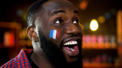Happy african-mexican man with french flag on cheek smiling, lottery results