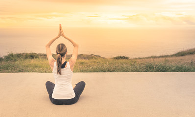 Woman meditating outdoors with a beautiful ocean view 