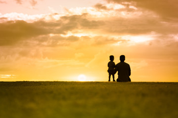 Silhouette of father and son watching the sunset. 