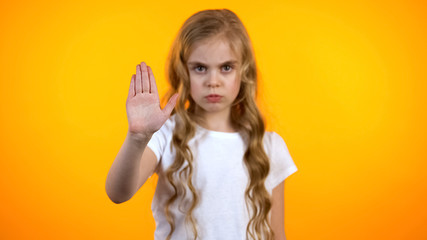 Teen girl showing stop gesture to cam, children rights protection, stop violence