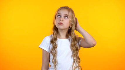 Pretty schoolgirl scratching head feeling uncertain about choice, lack of ideas