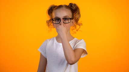 Cute schoolgirl adjusting eyeglasses and looking to camera, kids ophthalmology