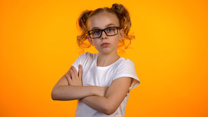 Adorable girl in eyeglasses looking to camera with hands crossed on chest, nerd