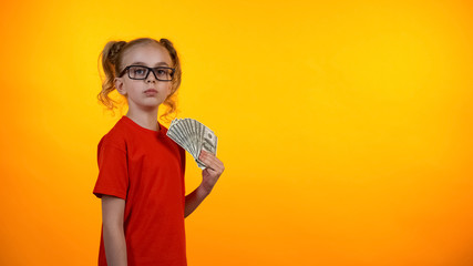 Cute wunderkind girl holding bunch of dollar cash, nerd winning grant, income