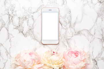 Fototapeta na wymiar Mobile phone with a white and pink piony flowers on a marble background