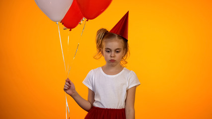 Sad preteen girl holding balloons, celebrating birthday alone, having no friends
