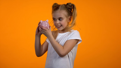 Pretty girl looking at piggybank, financial literacy, savings for future deposit