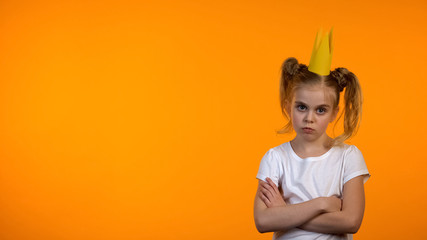 Naughty schoolgirl in paper crown and hands crossed on chest looking to cam