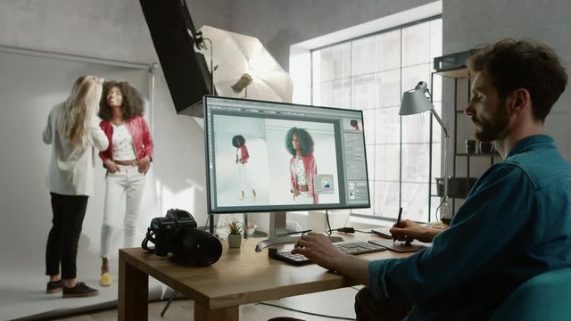 Backstage of the Photoshoot: Make-up Artist Applies Makeup on Beautiful Black Girl. Photo Editor Works on Desktop Computer Retouching Photo with Image Editing Software. Fashion Internet Magazine 