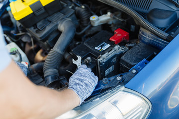 Hands of mechanic repairing the engine of the special keys (wrenches and ratchets). Professional mechanic in gloves working in a car service.