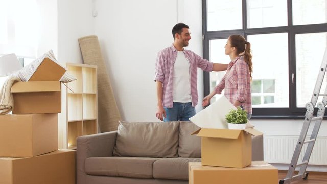 accommodation, repair and real estate concept - happy couple with stuff in cardboard boxes moving to new home and hugging