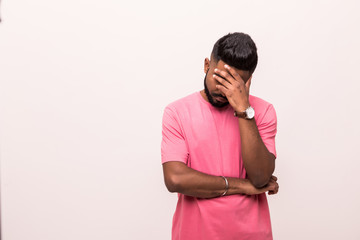 Young indian man in gloomy mood with head on hands and ruffled hair