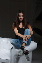 Pretty brunette posing sitting on a sofa.