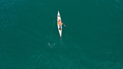 Aerial drone photo of fit man practising sport canoe in calm water sea