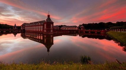 Schloss am Wasser beim Sonnenuntergang im Sommer. Langzeitbelichtung. Abend rot