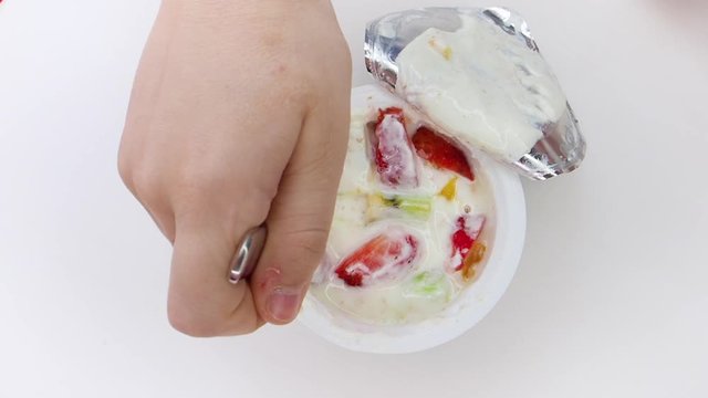 yogurt and fruits. Children's hand scoops up yogurt with fruits from a jar with a spoon. View from above. Slow motion