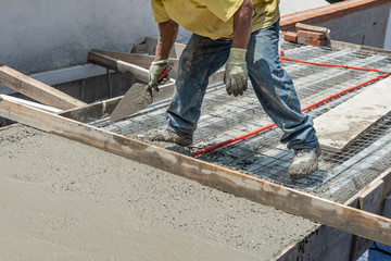 Bricklayer leveling a cement roof. Stretching out to smooth the casted concrete mix  