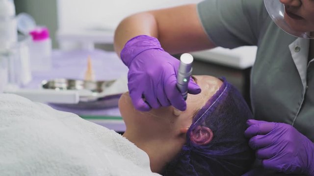 Cosmetologist is applying serum on face of young woman and performing  bb glow treatment
