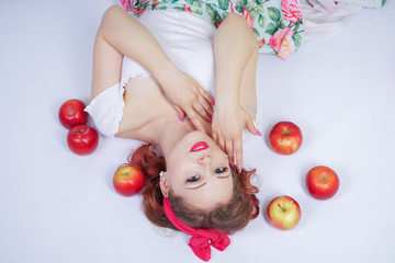 Fototapeta na wymiar pretty pin up woman with red apples. vintage female wearing retro summer dress on white studio background