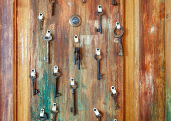 Large collection of hanging old keys on shabby wooden doors and with modern peephole