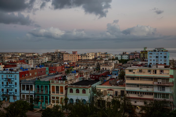 Obraz premium Aerial view of the residential homes in Havana City, Capital of Cuba, during a colorful cloudy sunrise.