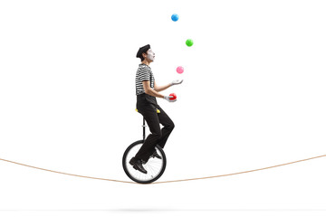 Mime riding a unicycle on a rope and juggling with balls - obrazy, fototapety, plakaty