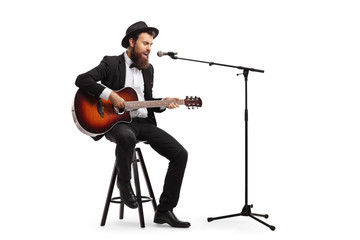 Musician singing on a microphone and playing an acoustic guitar