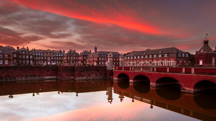 Schloss am Wasser beim Sonnenuntergang, Brücke, See, roter Himmel