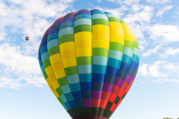 Obraz premium Two hot air balloons floating under vibrant blue sky with puffy white clouds