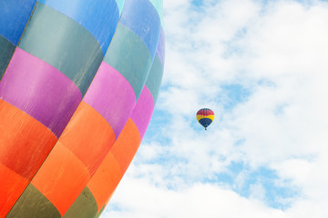 Two hot air balloons floating under vibrant blue sky with puffy white clouds