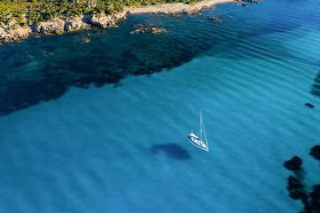 View from above, stunning aerial view of a sailing boat floating on a beautiful turquoise clear sea. Maddalena Archipelago National Park, Sardinia, Italy.
