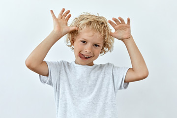 Making face,funny  foolishes portrait of Little child boy, against white background.