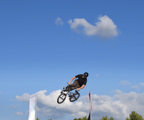 Sprung mit dem BMX-Rad in den blauen Himmel mit Wolken