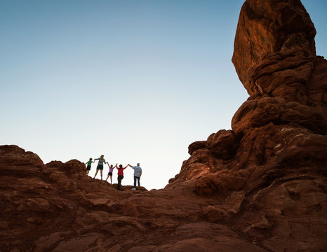 Family enjoying hiking and holding hands at sunset in Moab, Utah