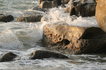 Seawaves hitting rocks on beach.