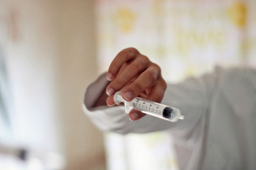 Doctor dressed in white holding a syringe.