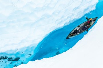 Ice climber canoeing in narrow ice canyon from above.