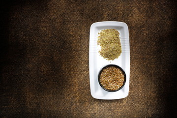 Flaxseeds in a plate on decorative sackcloth. Ground flax seeds and whole seeds. A product rich in...