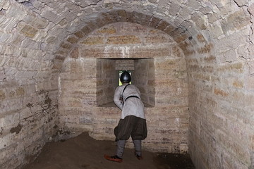 A boy in a historical Viking costume looks into a loophole of the fortress inside the fortress wall
