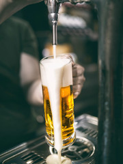 waiter serving cold beer from a tap while foam falls