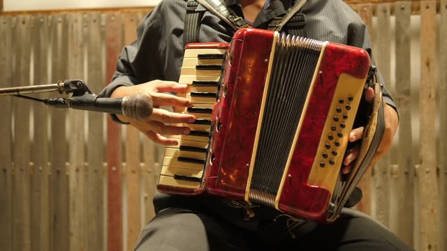Video clips of middle-aged men sitting Accordian on the stage happily.