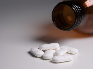 White medicine pills with brown bottle, shallow focus