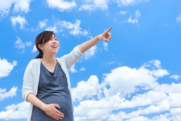 青空　妊婦　指差し　笑顔