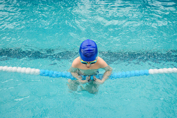 top view of a 7-year boy playing and swimming in the swimming pool