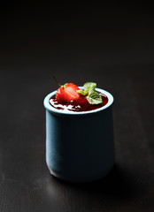 Strawberry and mint desert of fresh ripe  homemade yogurt pana cotta in blue jar on dark background