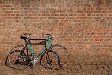 Fototapeta na wymiar Retro Vintage Commuting Bicycle park and lean against rough old exterior brick wall. Eco friendly and urban lifestyle concept for transportation in city and old town. 